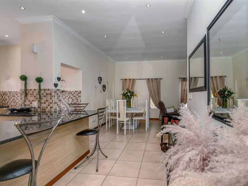 Open-plan living and dining area featuring a modern kitchen with granite countertops, a breakfast bar, and neutral tiled flooring throughout.