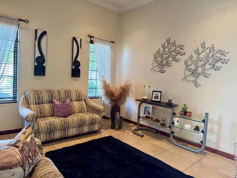 A comfortable living room featuring neutral tiled flooring, large windows with blinds, and classic skirting boards, providing a functional and well-lit space.