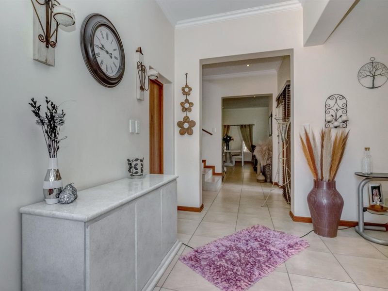 A bright and welcoming entrance hallway featuring neutral tiled flooring, coving, and a clear transition into the main living areas of the home.