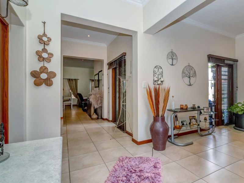 A bright and spacious hallway featuring neutral tiled flooring, recessed lighting, and access to adjoining living areas through wide archways.