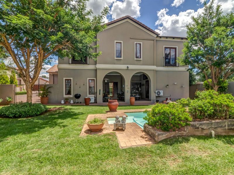 Rear view of a two-story house featuring a covered patio, swimming pool, and a well-maintained garden area.
