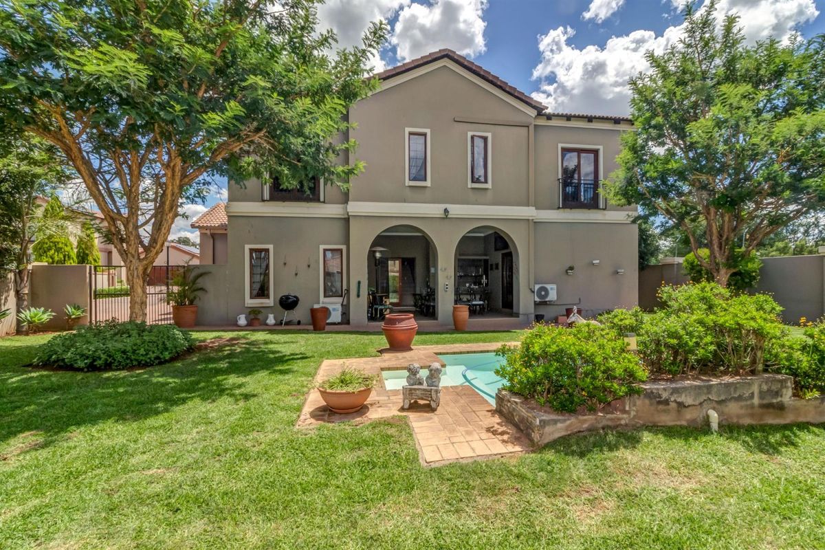 Rear view of a two-story house featuring a covered patio, swimming pool, and a well-maintained garden area.