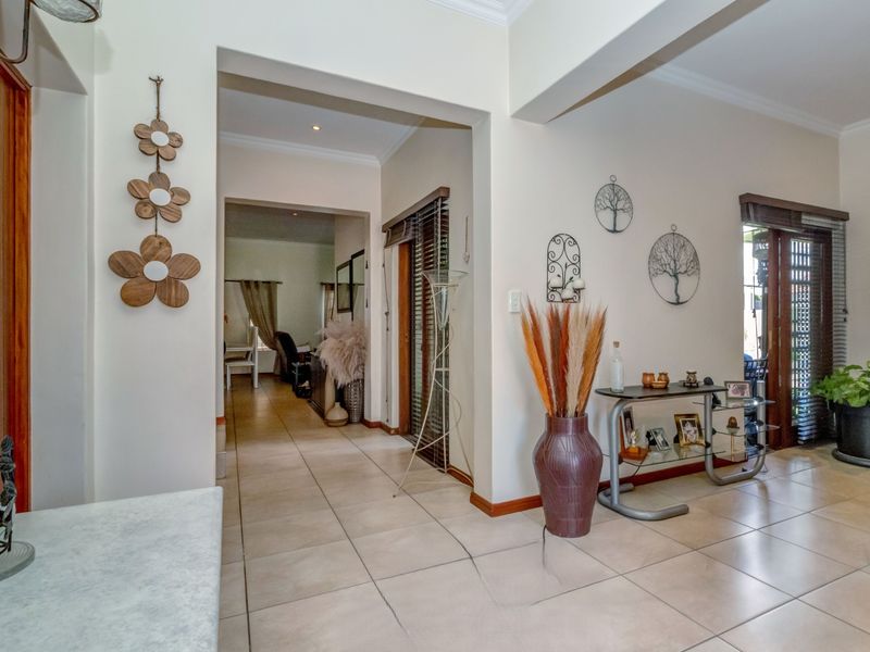 A spacious tiled hallway featuring recessed lighting and access to adjoining living areas, with neutral wall finishes and wooden window blinds.