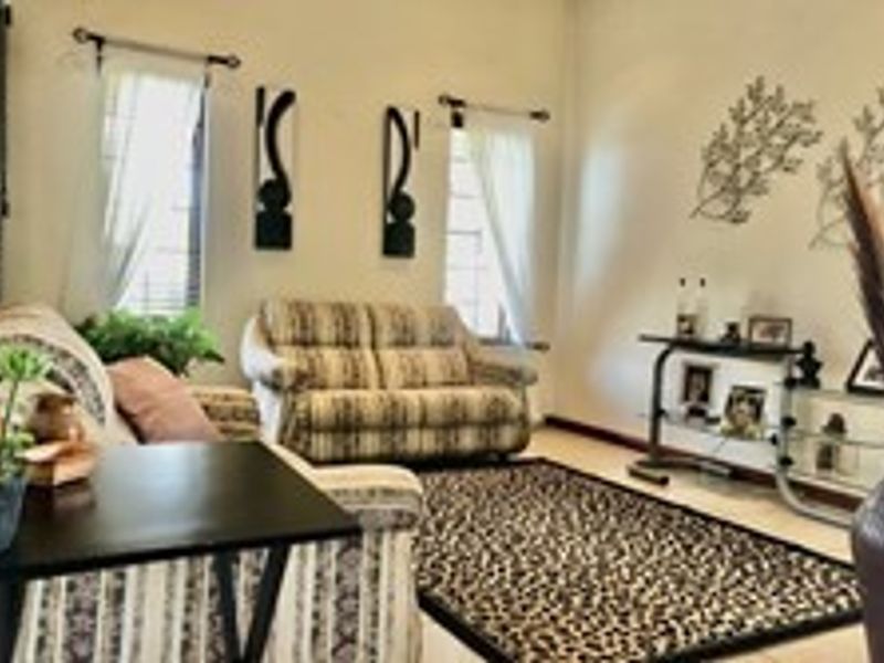 A cozy living room featuring tiled flooring and natural light from dual windows, providing a comfortable space for relaxation.
