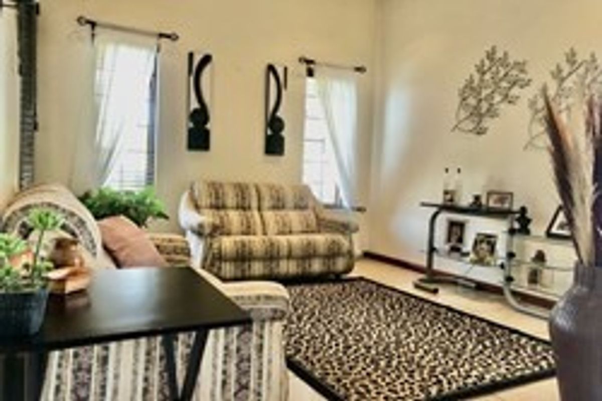 A cozy living room featuring tiled flooring and natural light from dual windows, providing a comfortable space for relaxation.