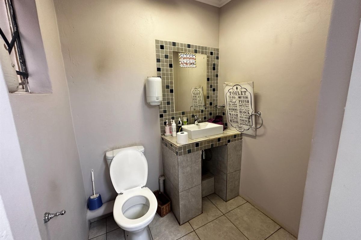 A functional commercial restroom featuring a tiled vanity with a vessel sink, a standard toilet, and mosaic tile backsplash.