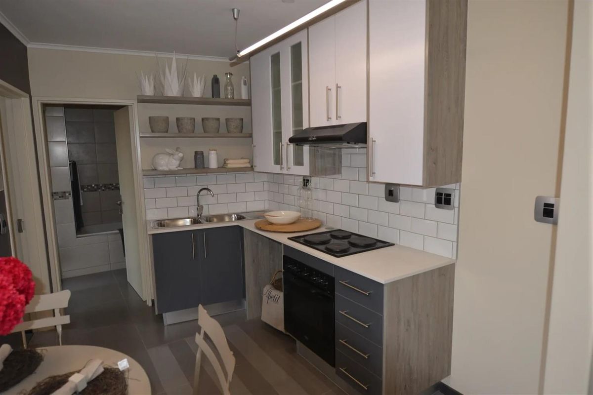 Modern kitchen featuring two-tone cabinetry, subway tile backsplash, built-in oven, electric hob, and extractor fan, with an adjacent view into the bathroom.