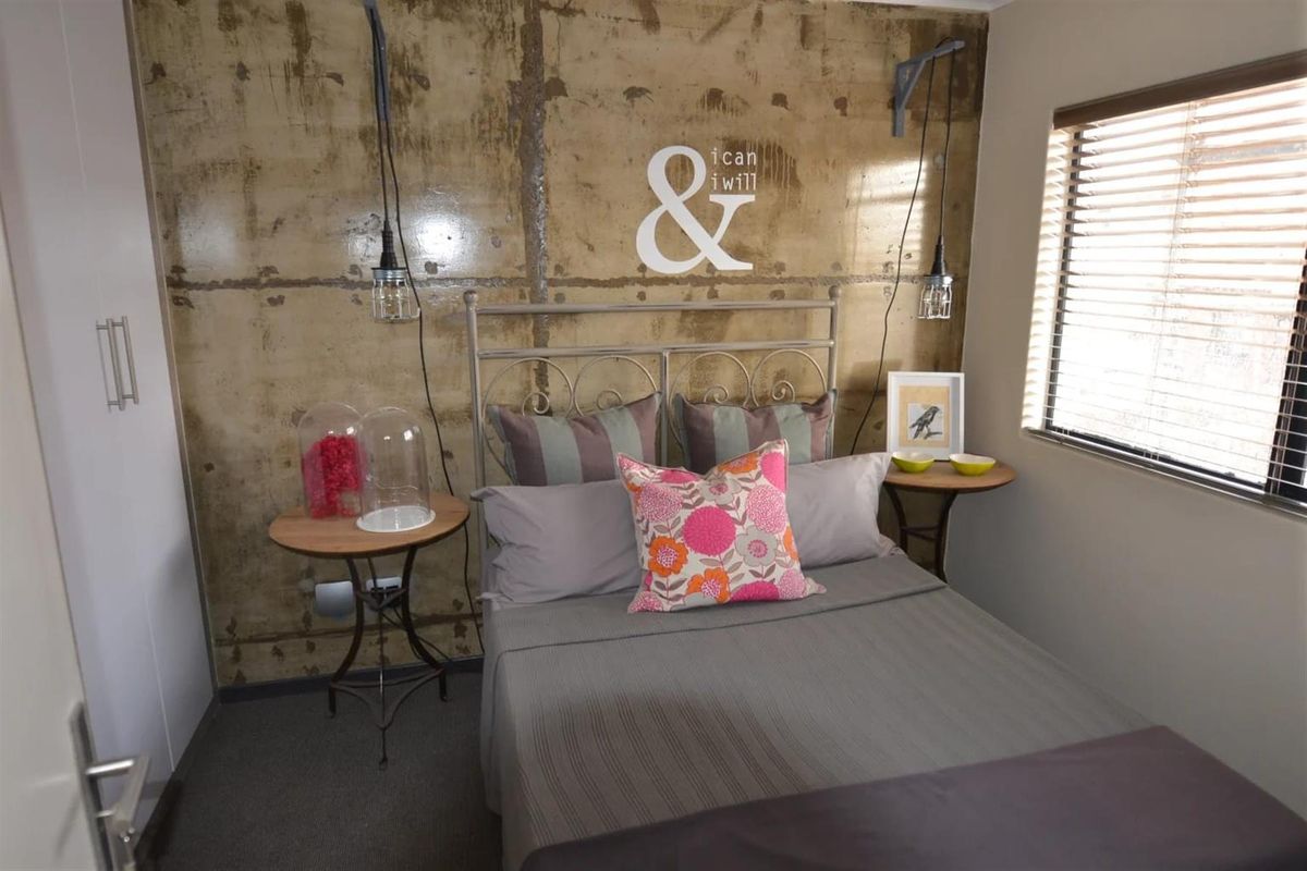 A bedroom featuring a textured feature wall, built-in wardrobe, and window with fitted blinds.
