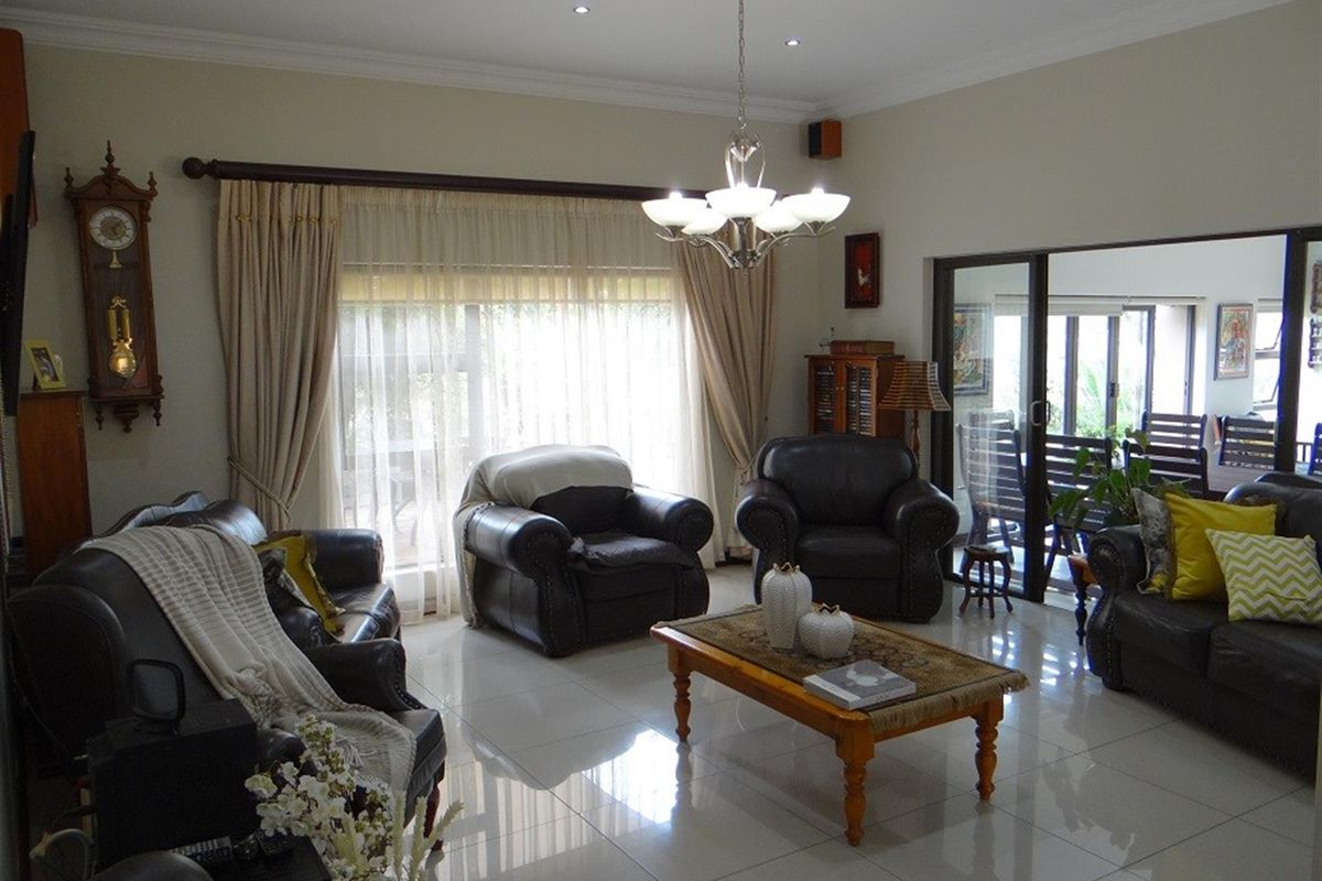 Spacious living room featuring polished porcelain floor tiles, recessed downlighting, and large sliding glass doors providing access to an outdoor patio area.