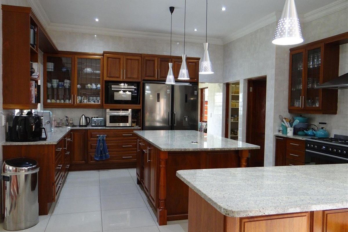 Spacious kitchen featuring rich timber cabinetry, granite countertops, a large central island, and integrated stainless steel appliances.