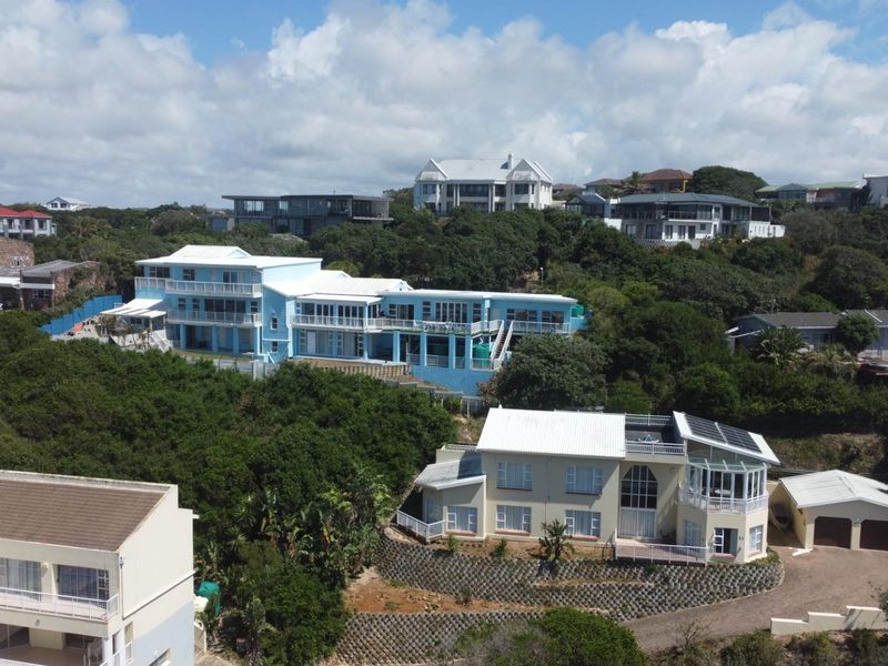 Aerial view of a coastal residential area featuring multi-level homes with balconies, solar panels, and landscaped surroundings.