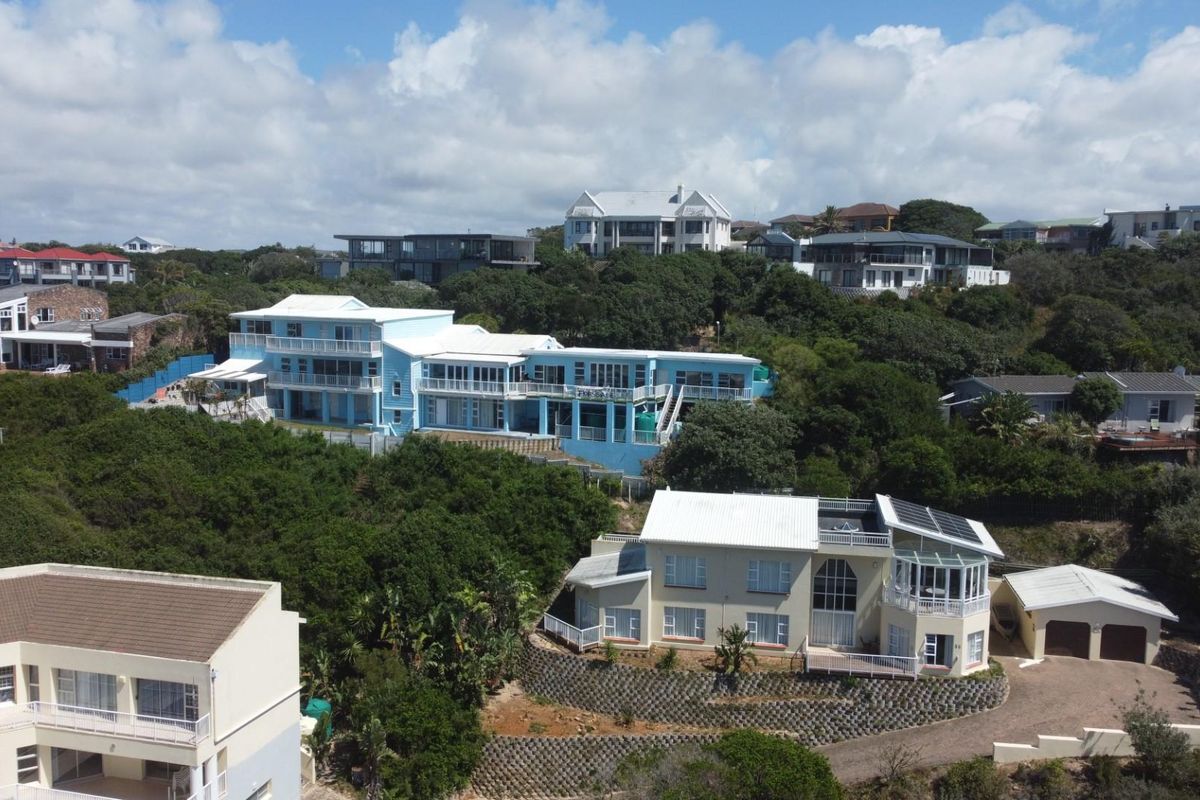 Aerial view of a coastal residential area featuring multi-level homes with balconies, solar panels, and landscaped surroundings.