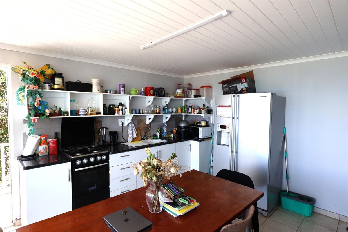 A functional kitchen area featuring open shelving, a built-in stove, and tiled flooring, providing a practical space for meal preparation and dining.