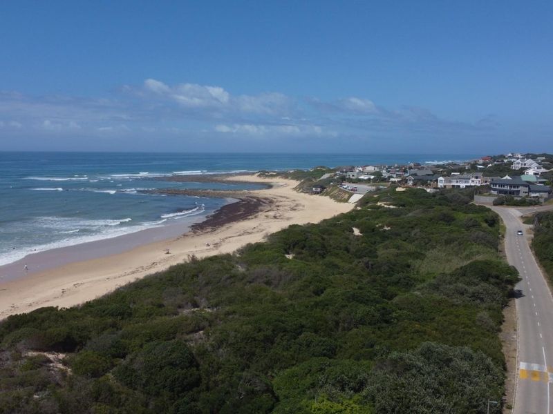 Aerial view of the coastal landscape, featuring the sandy beach, ocean shoreline, and surrounding residential neighborhood infrastructure.