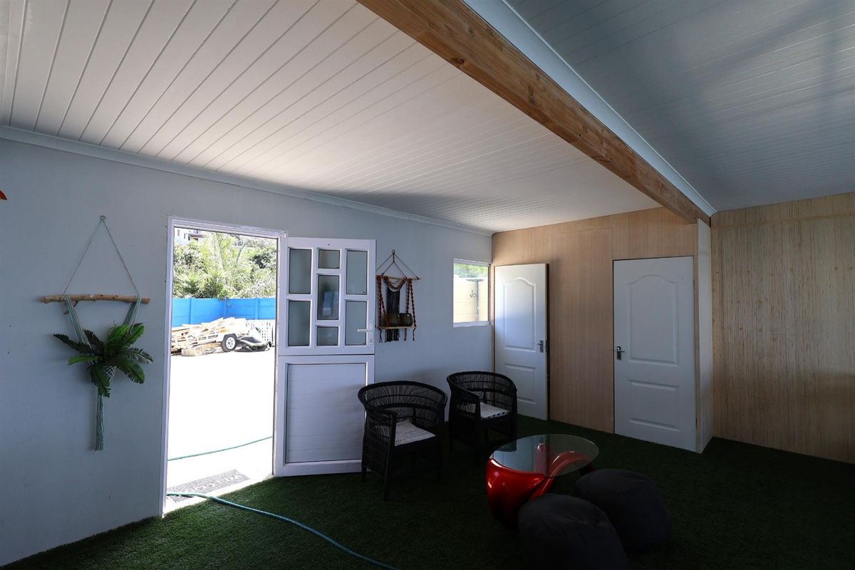 A versatile interior space featuring artificial turf flooring, timber-look wall paneling, and a stable-style door leading to an outdoor area.