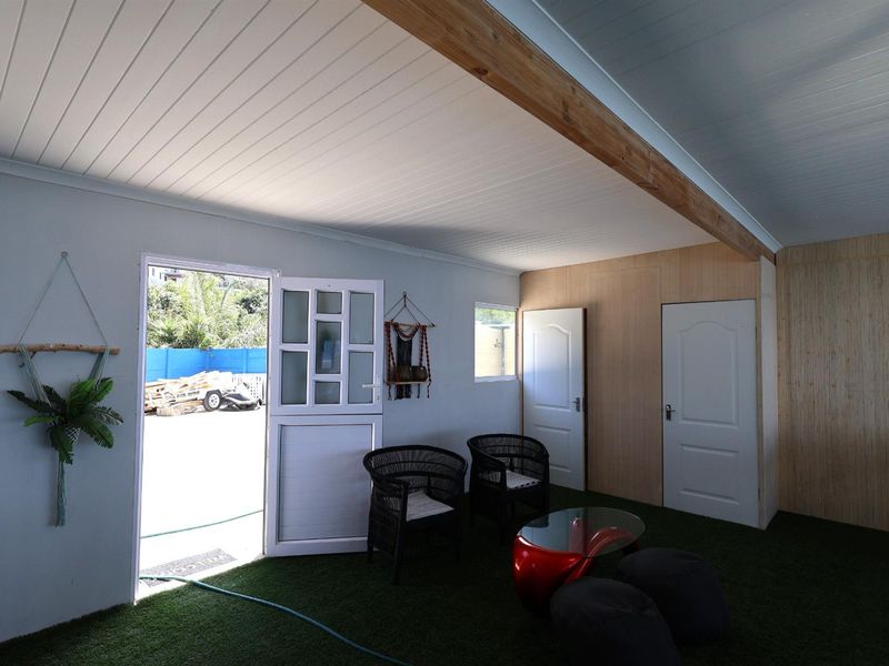 A versatile interior space featuring artificial turf flooring, timber-look wall paneling, and a stable-style door leading to an outdoor area.