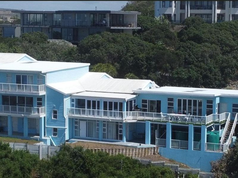 Aerial view of a large multi-level residential property featuring extensive wrap-around balconies, white metal railings, and a light blue exterior finish.