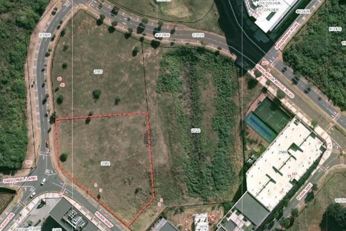 Aerial view of a vacant commercial land plot with defined boundaries, situated in a developed urban area with surrounding road infrastructure.