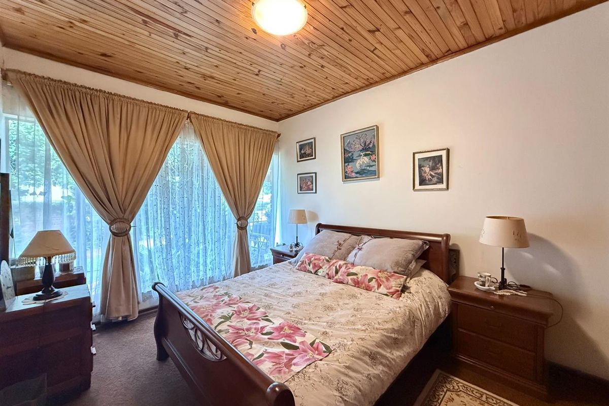 A bedroom featuring a timber-clad ceiling, carpeted flooring, and large windows with access to the exterior.