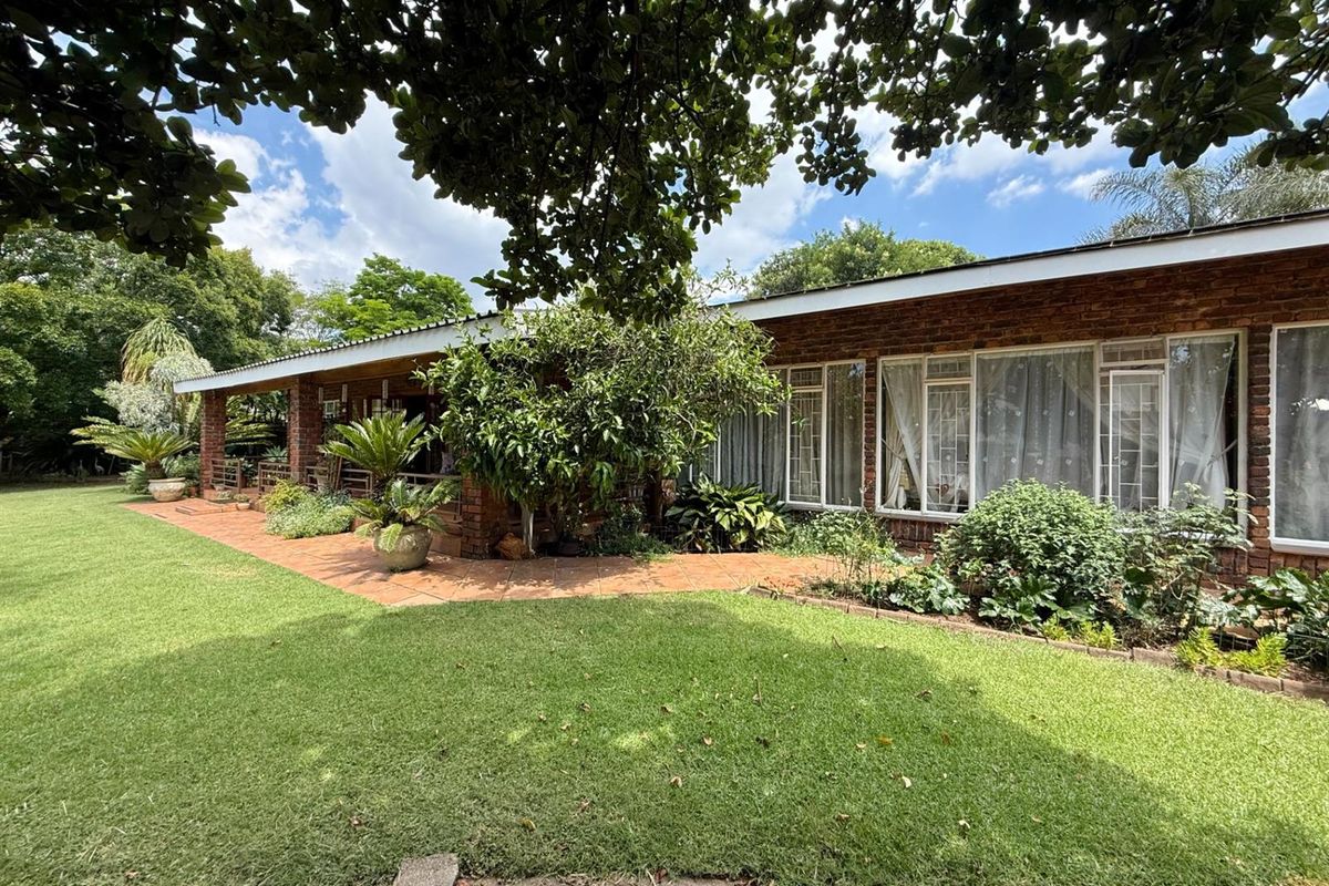 A view of the rear exterior facade featuring a brick finish, a covered patio area, and a well-maintained garden lawn.