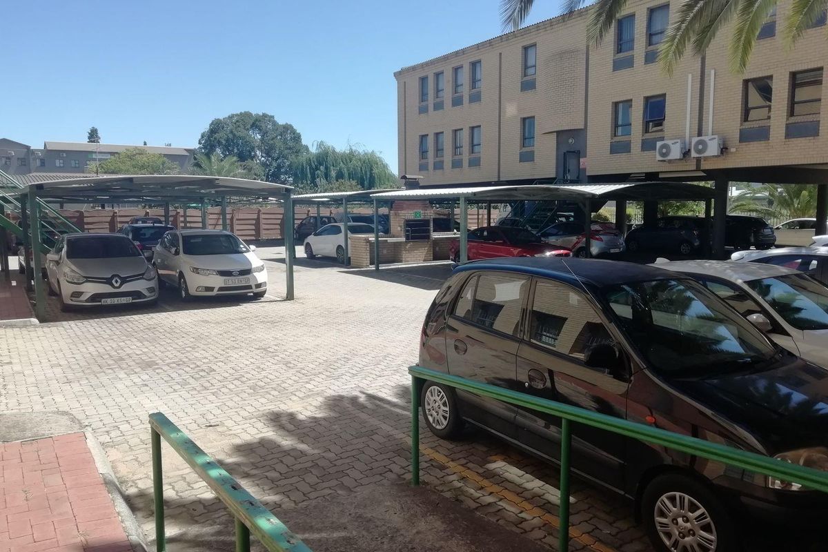 Commercial parking area featuring covered carports, paved surfacing, and direct access to the multi-story office building facade.