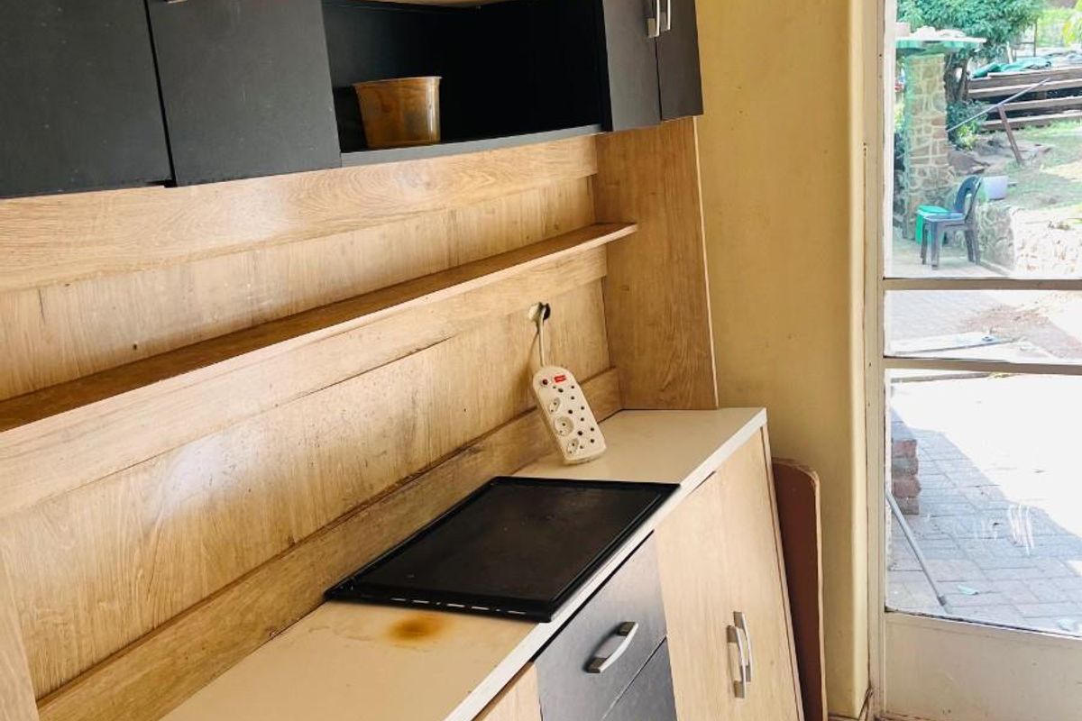 A compact kitchen area featuring two-tone cabinetry, a built-in cooktop, and direct access to the outdoor patio area.