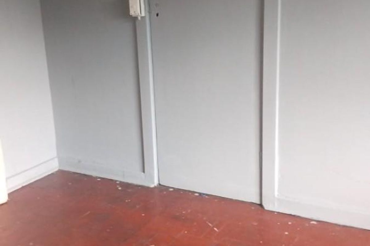 An empty room featuring original parquet flooring and painted walls with a single interior door.
