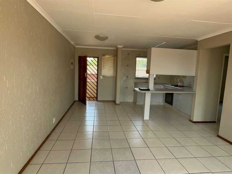 An open-plan living and kitchen area featuring tiled flooring, built-in cabinetry, and a breakfast counter, offering a functional layout ready for personalization.
