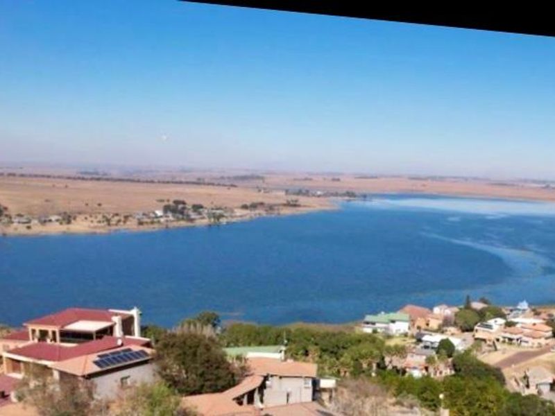An aerial view of the property and surrounding landscape, featuring a large dam and residential area.