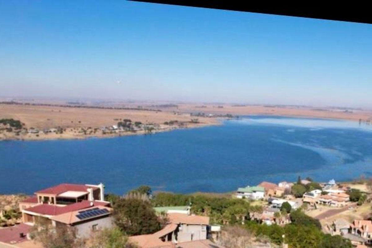 An aerial view of the property and surrounding landscape, featuring a large dam and residential area.