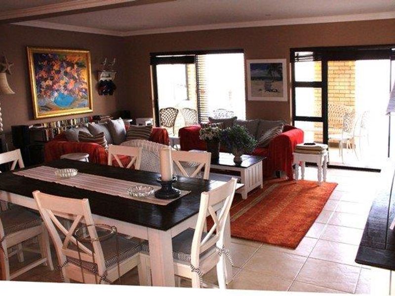 Open-plan living and dining area featuring tiled flooring, crown molding, and large sliding glass doors providing access to the patio.
