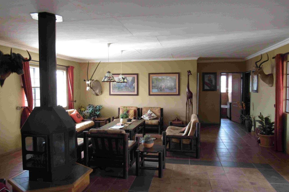 Spacious living room featuring a central freestanding fireplace, tiled flooring, and direct access to the hallway.
