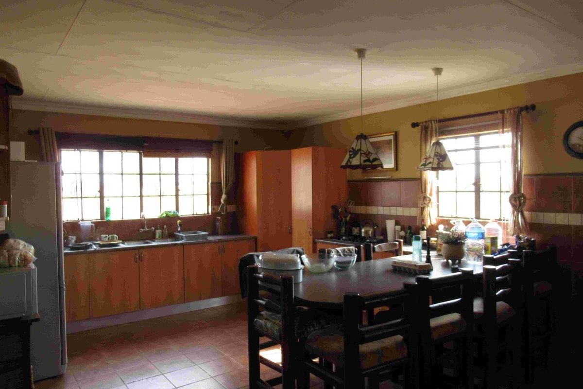A functional kitchen featuring wooden cabinetry, tiled splashbacks, and a central dining area with natural light from multiple windows.