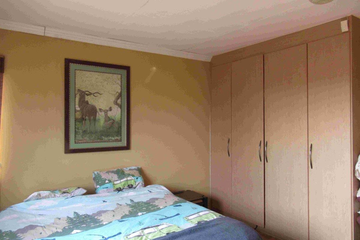 A bedroom featuring built-in wooden cupboards and neutral wall finishes, providing functional storage space.