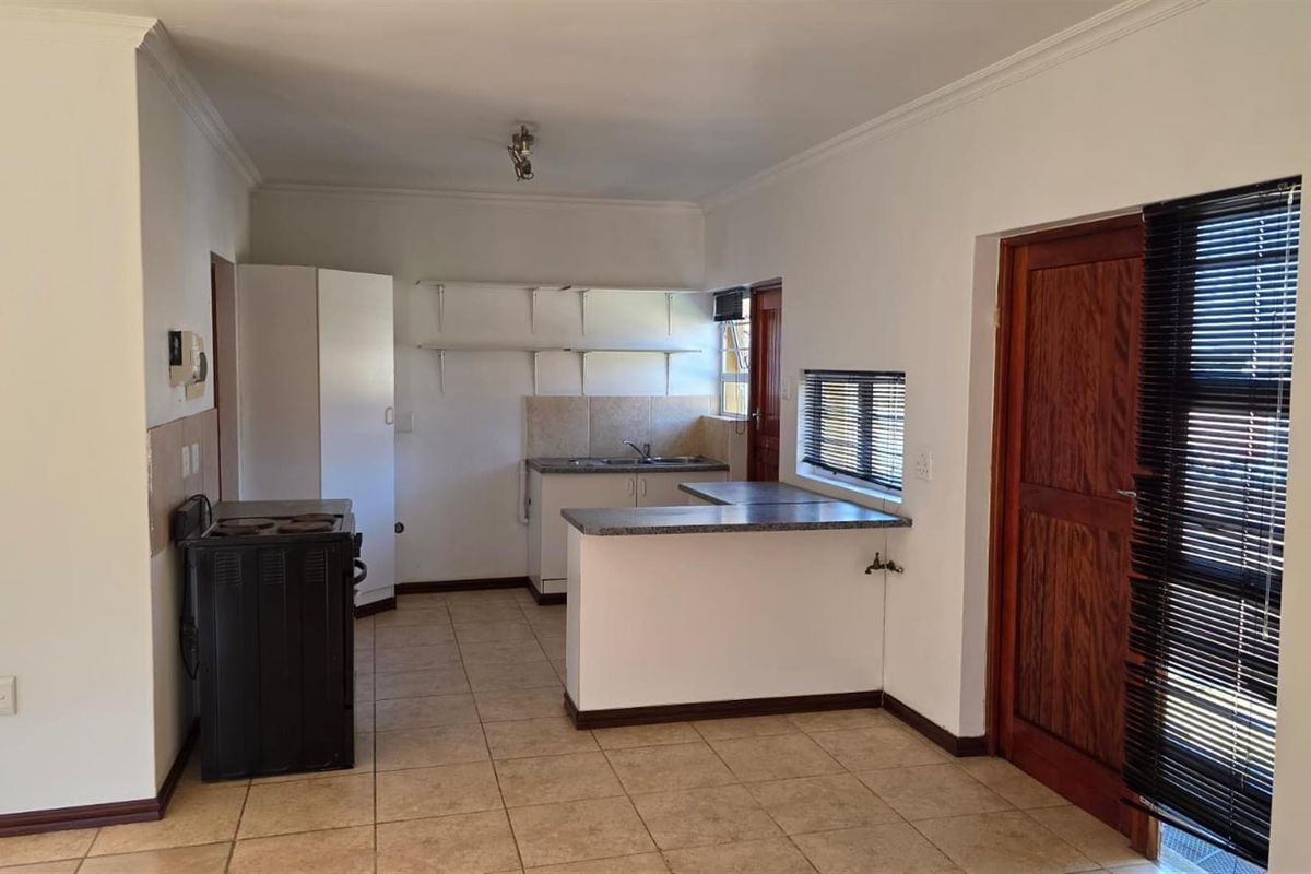 A functional kitchen featuring tiled flooring, a breakfast bar, built-in sink area, and open shelving, providing a practical layout for daily meal preparation.