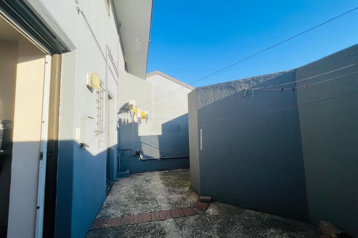 A private rear courtyard area featuring concrete paving, perimeter boundary walls, and external utility access points.
