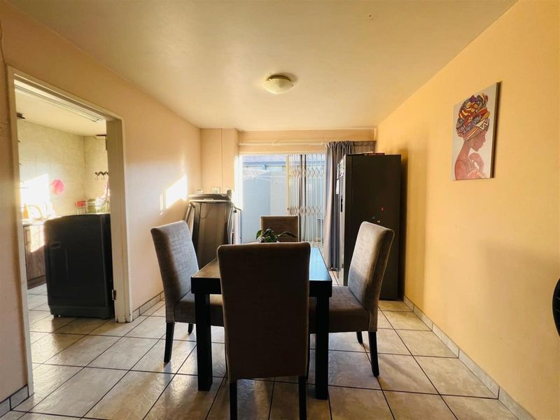 A dining area featuring tiled flooring and a sliding door leading to an outdoor space, with an adjacent view into the kitchen area.