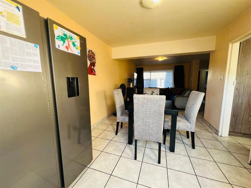 Open plan living and dining area featuring tiled flooring and a neutral color palette, providing a functional space for daily living.