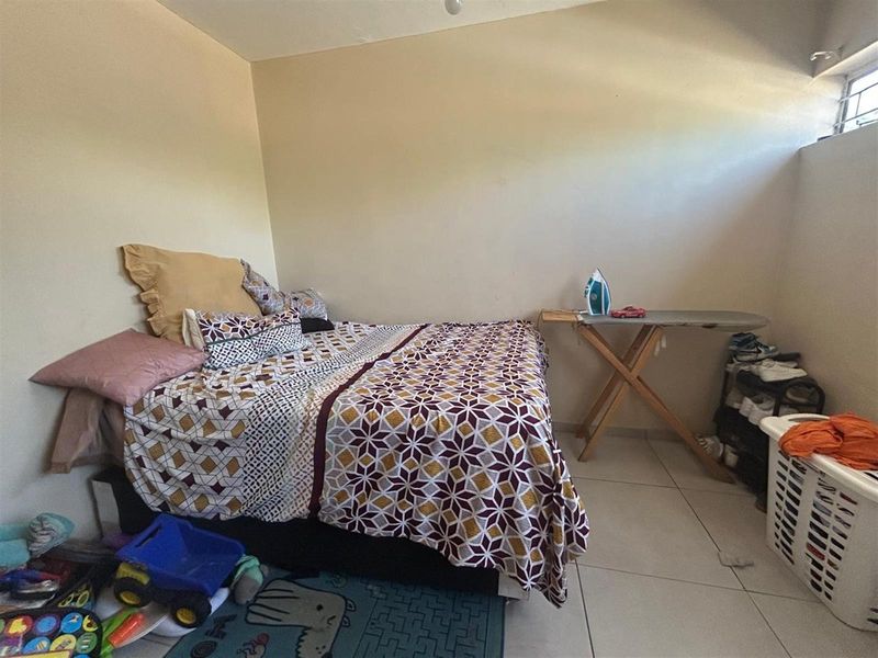 A functional bedroom featuring tiled flooring and a high-level window, providing natural light and a neutral base for potential updates.