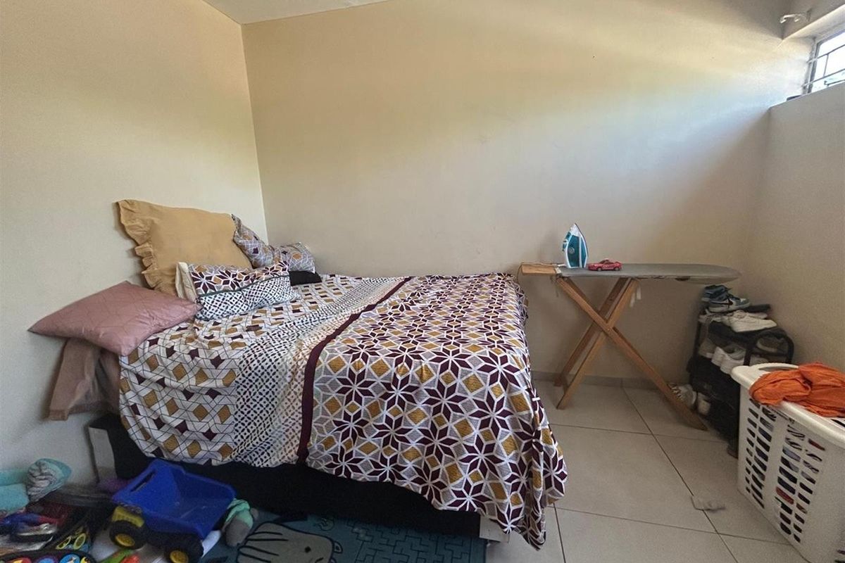 A functional bedroom featuring tiled flooring and a high-level window, providing natural light and a neutral base for potential updates.