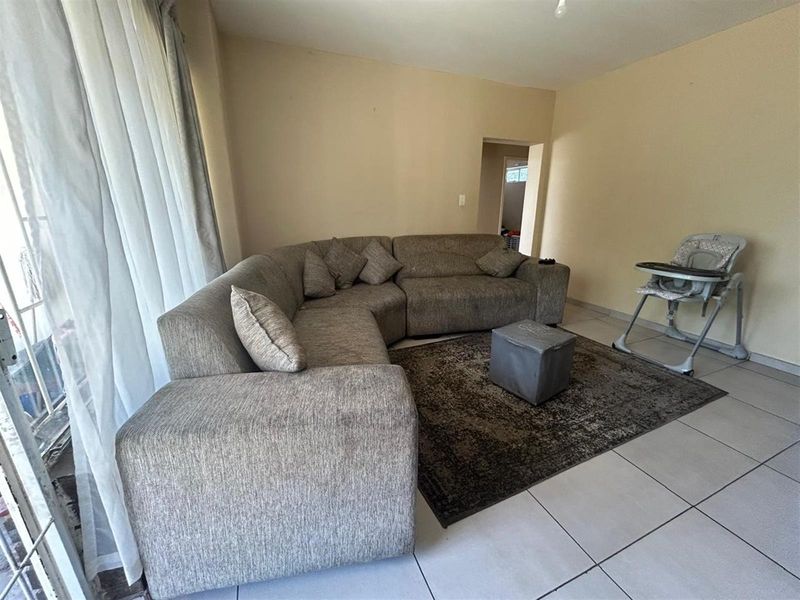 A living room area featuring neutral tiled flooring and a sliding glass door providing natural light.