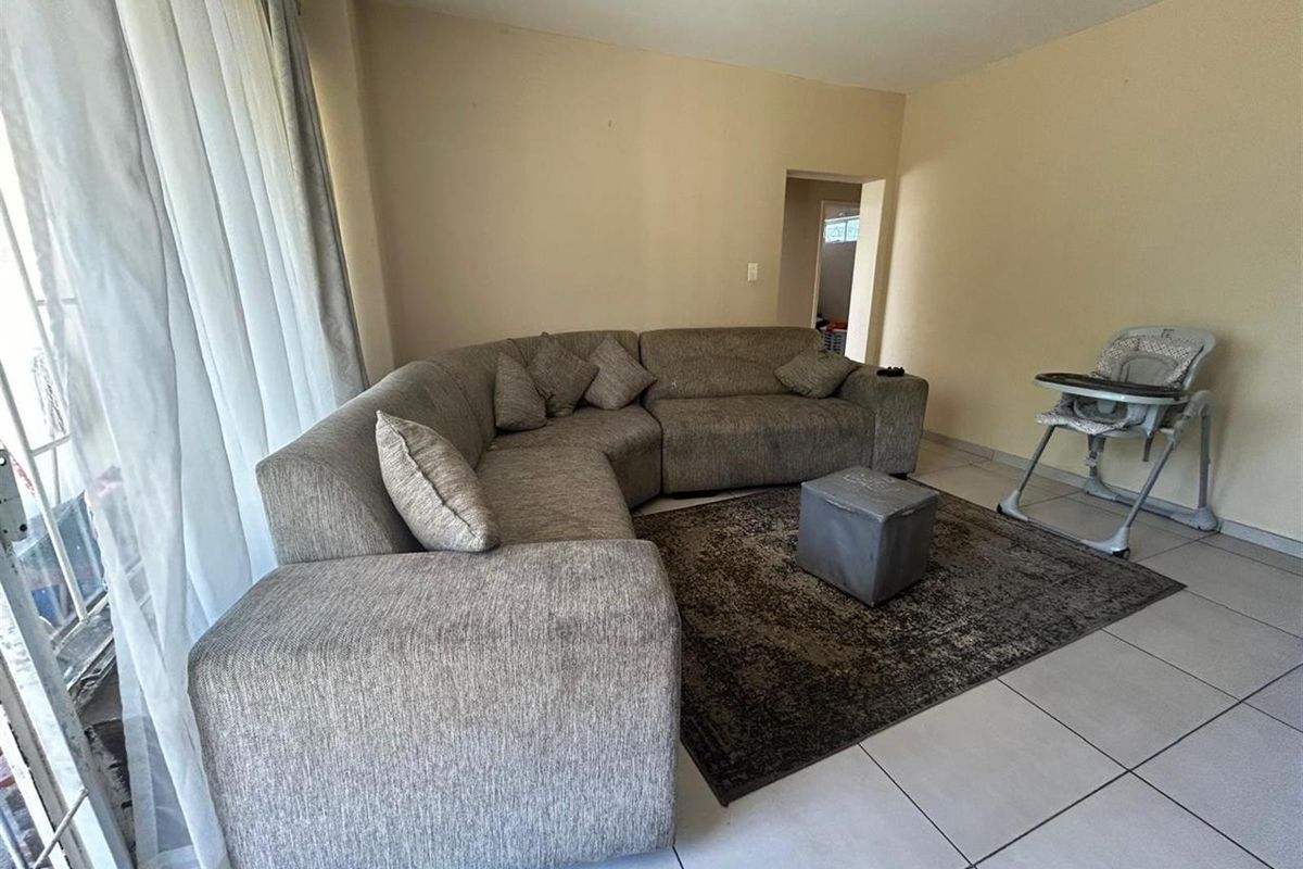 A living room area featuring neutral tiled flooring and a sliding glass door providing natural light.