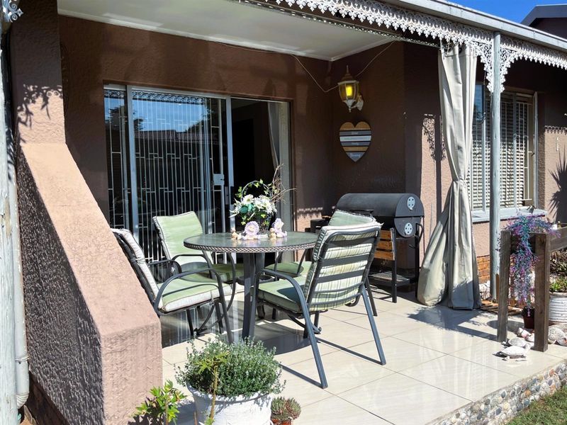 A covered patio area featuring tiled flooring, decorative metal eaves, and a sliding glass door providing access to the interior living space.