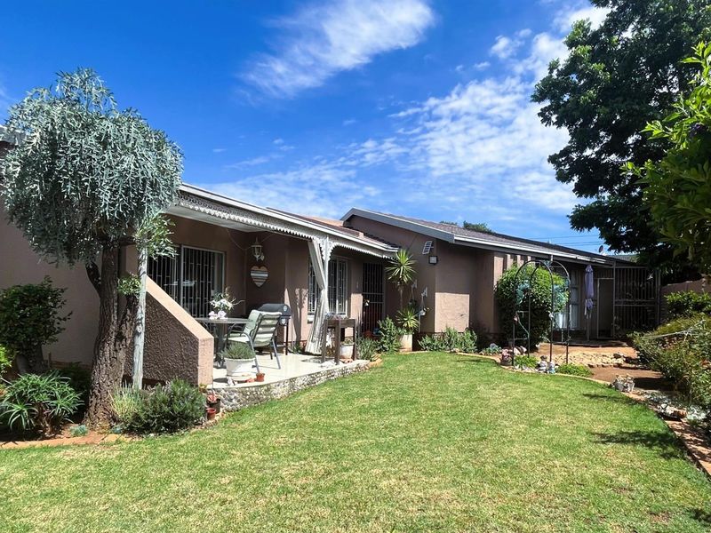 Rear view of the house featuring a covered patio area, security-fitted sliding doors, and a well-maintained garden space.