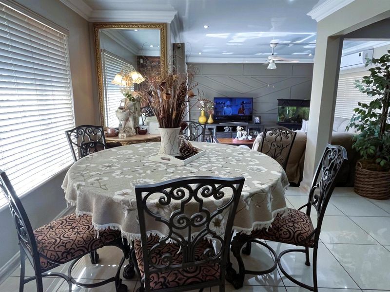 An open-plan dining and living area featuring tiled flooring, recessed ceiling lighting, and decorative wall paneling, creating a cohesive and functional living space.