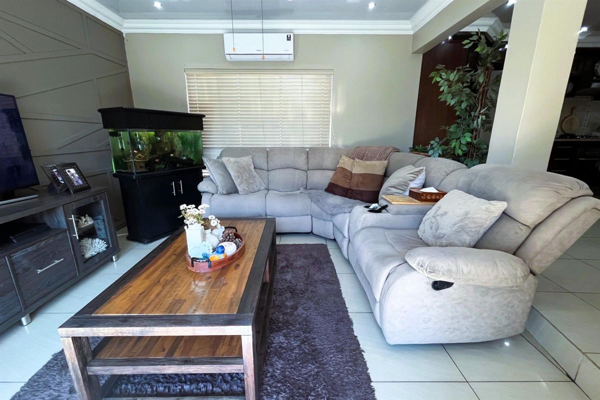A comfortable living room featuring tiled flooring, cove ceiling molding, and a wall-mounted split-system air conditioner.