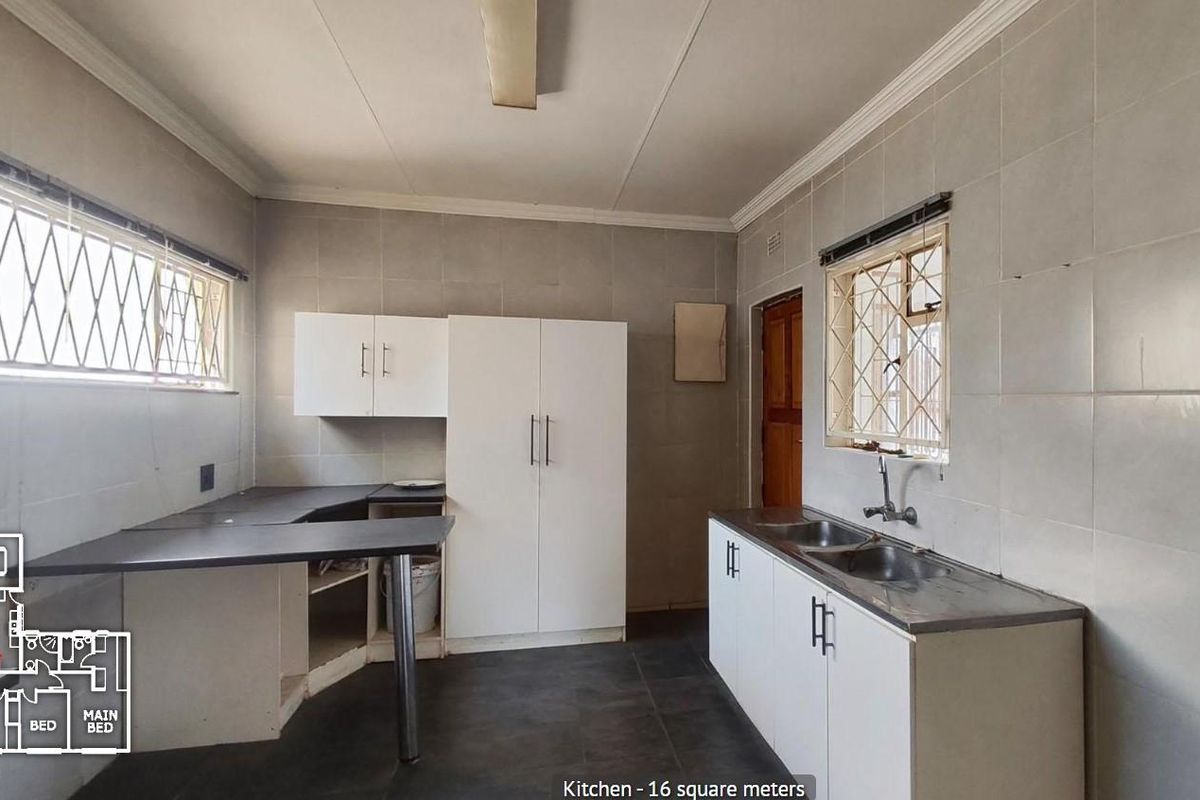 A functional kitchen space featuring tiled walls, built-in cabinetry, and a double stainless steel sink, ready for modernization and personal design updates.