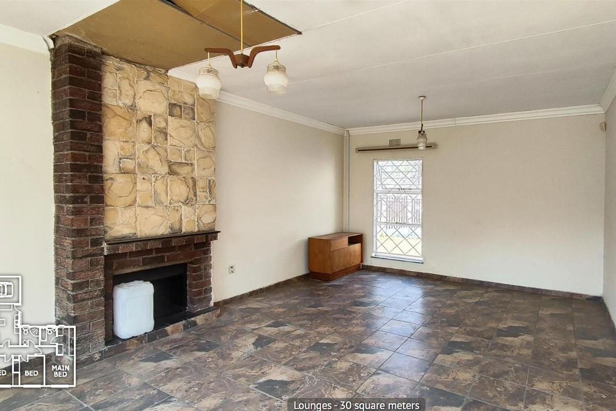 Spacious living room featuring a prominent stone fireplace, tiled flooring, and an arched entryway, offering a blank canvas for renovation.