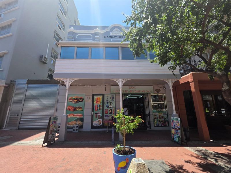 Front elevation of a historic commercial building featuring ornate ironwork, timber cladding, and large display windows at street level.