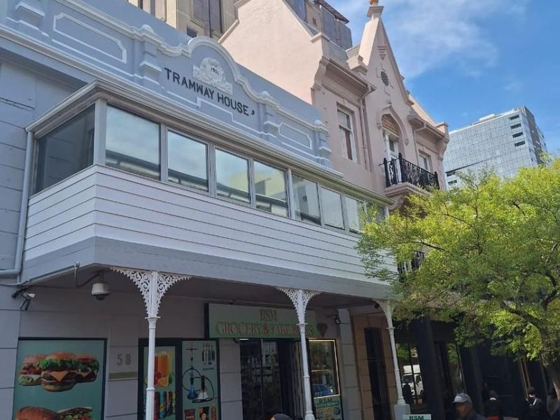 Street-level view of the historic Tramway House building, featuring a classic facade with ornate cast iron columns and an enclosed upper-level balcony.
